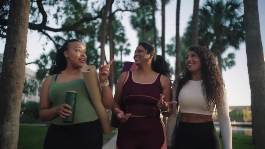 Three women in yoga clothes walking outdoors smiling
