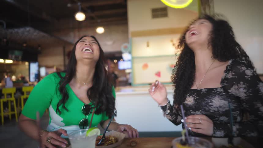 Two women and a man having fun at a restaurant table during the day