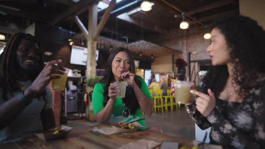 Friends are drinking and smiling as they eat together