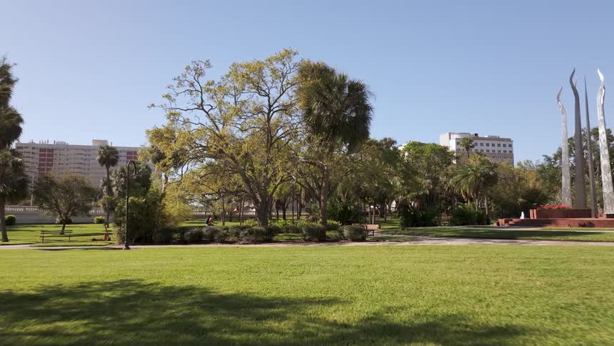A young woman rides her bicycle around a college campus park