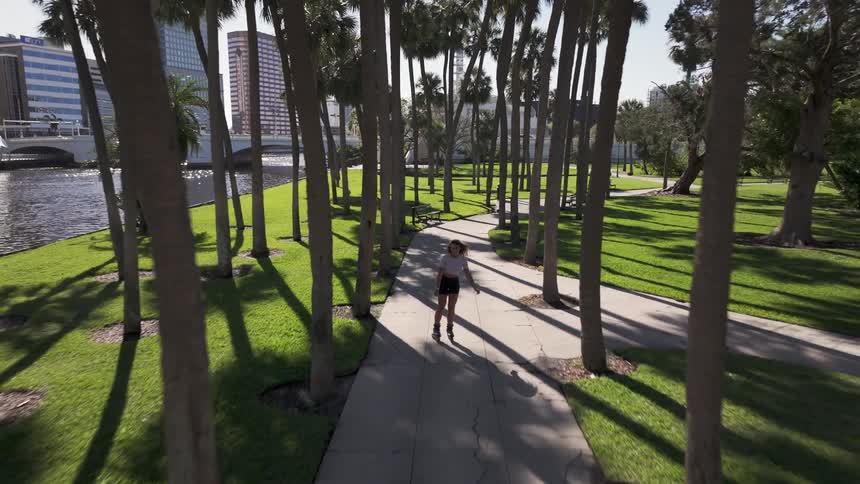 Aerial of woman rollerblading on a path at a waterfront park in the city