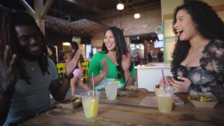 People sitting at a table with food and drinks are laughing and talking