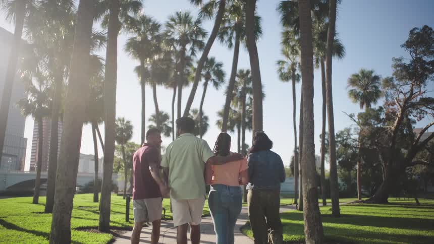 A small group of people is walking through a park in a city