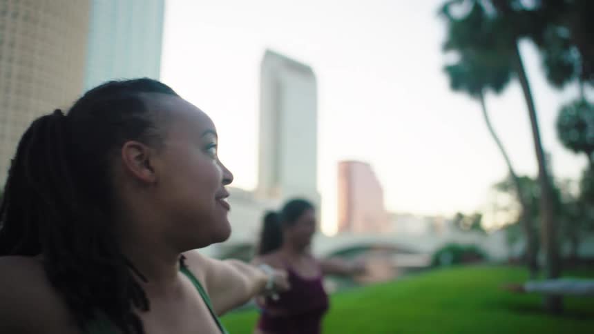 Women outdoors with arms outstretched in yoga stretch