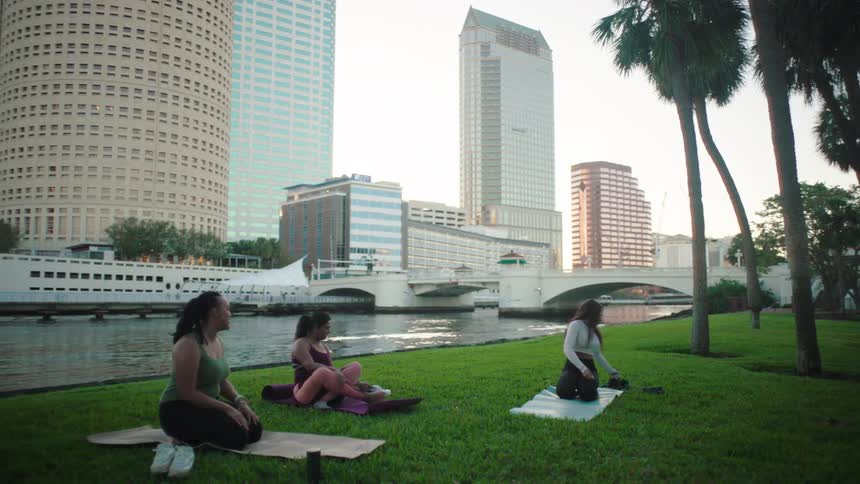 Women are sitting on yoga mats by the water
