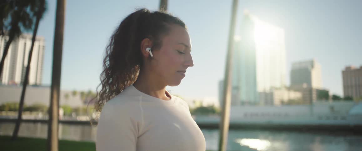 Woman outdoors and turning on earpods