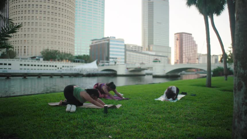 Three women outdoors on grass doing stretching