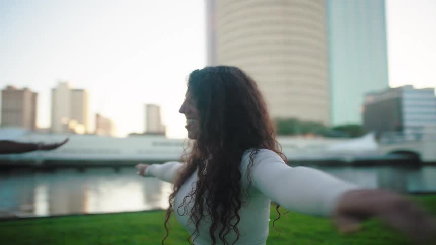 Women outdoors in a park by a lake doing arm stretching movements