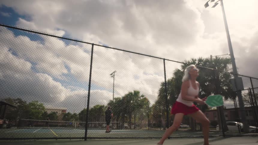 People are playing tennis on a court in a park