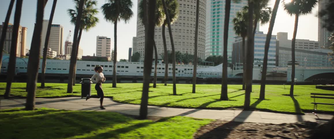 A woman is running in the park on a sunny day