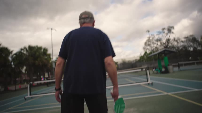 A man swings his racket while playing pickleball