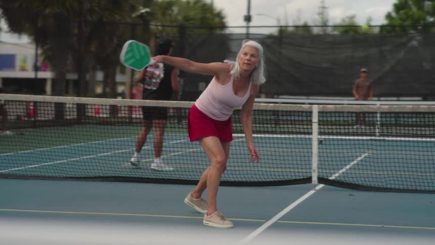Woman in red skirt and other people playing on an outdoor court