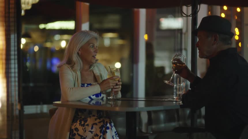 A man and woman toast their glasses and drink
