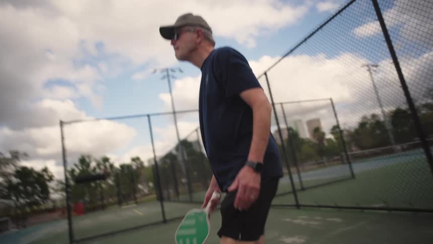 A man serves a tennis ball in a tennis court to someone else