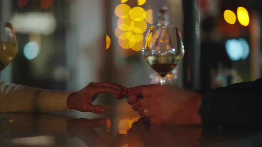 Couple holding hands on a table with glasses of wine