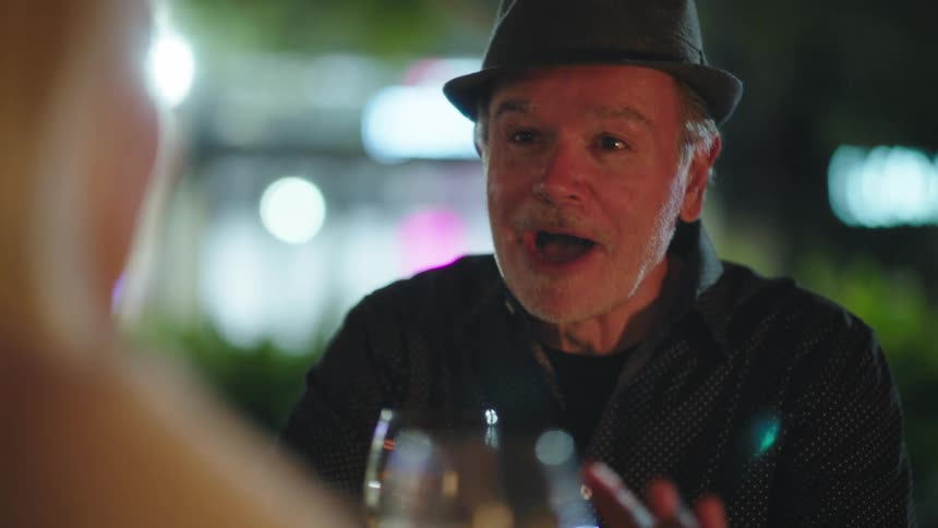 Elderly man sitting talking to another person at night