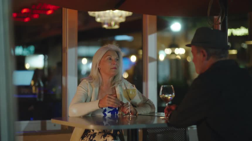 A man and woman have drinks outdoors by the restaurant