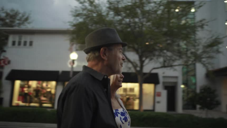 Elderly couple walking together on a city sidewalk in the late afternoon