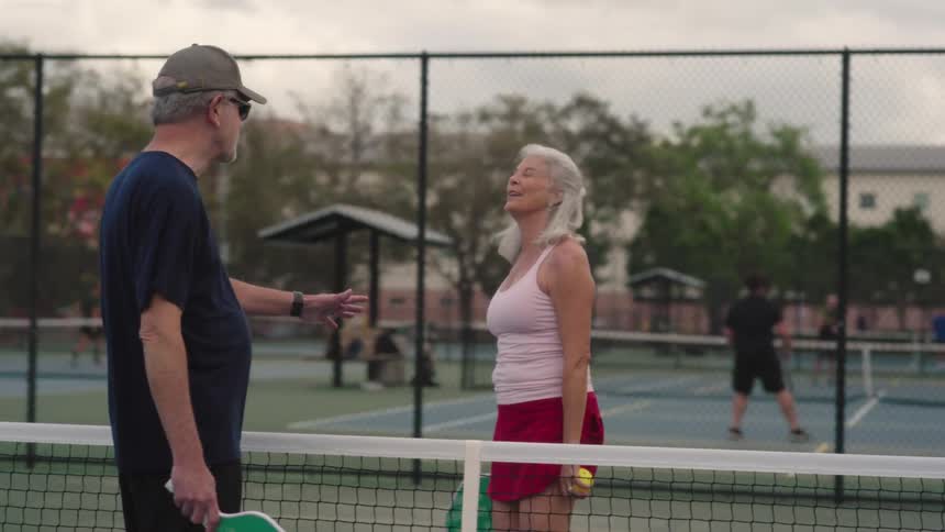 Elderly couple talking on an outdoor tennis court