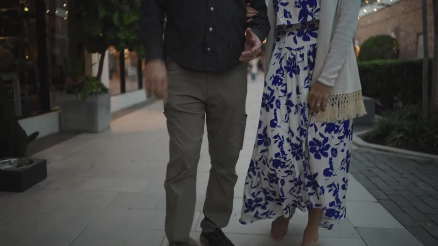 Two people walking outdoors with a woman wearing a floral dress