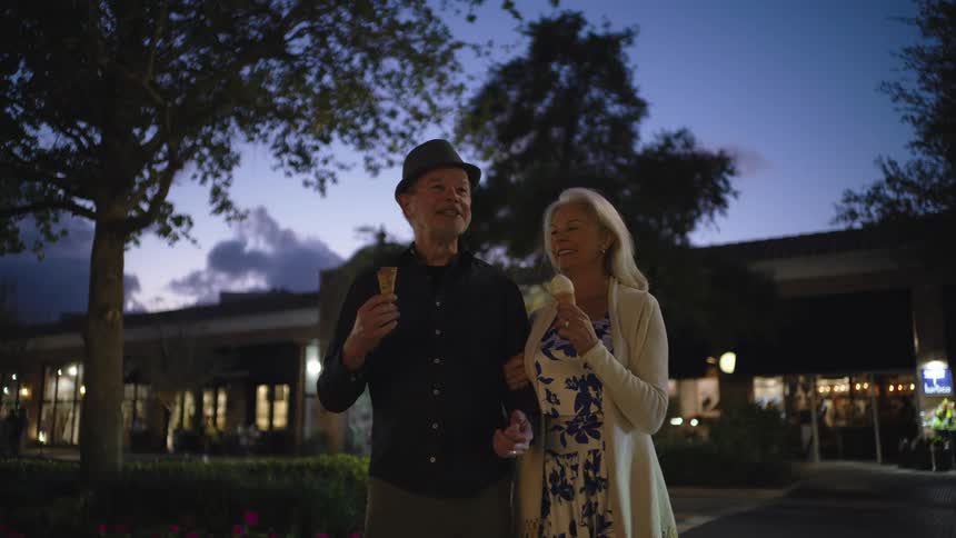A couple are walking and eating ice cream at sunset