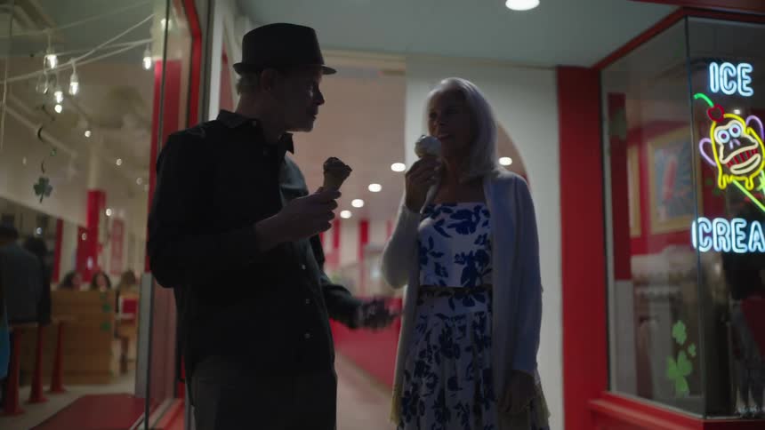 Elderly couple leaving an ice cream shop eating ice cream