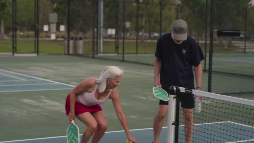 A man and woman talk and carry rackets on the court
