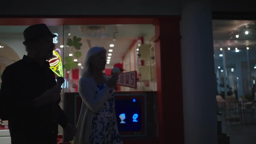 Two people eat ice cream and walk at night