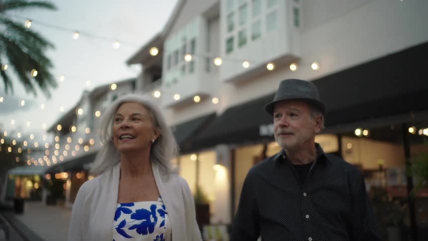 A man and woman are talking as they walk by the stores