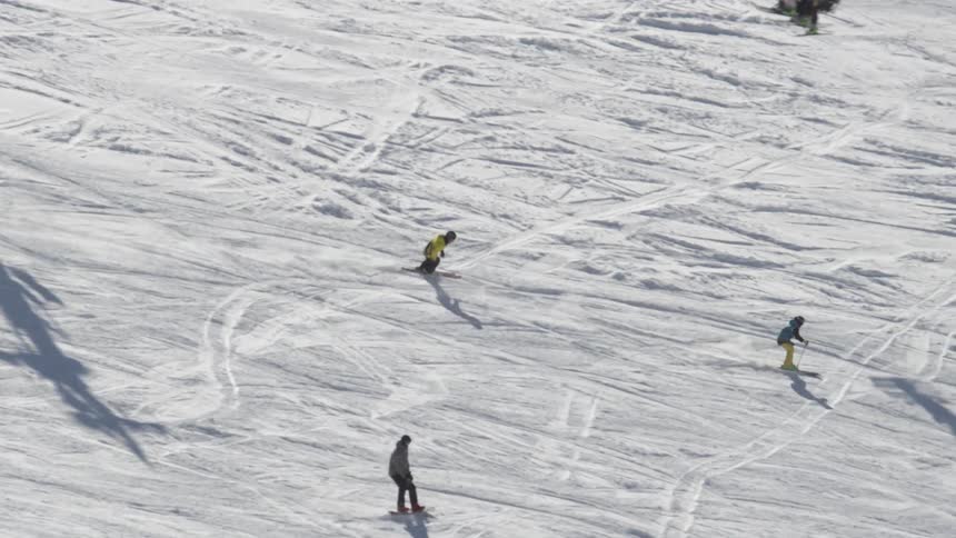 Skiers and snowboarders descend a snowy mountain
