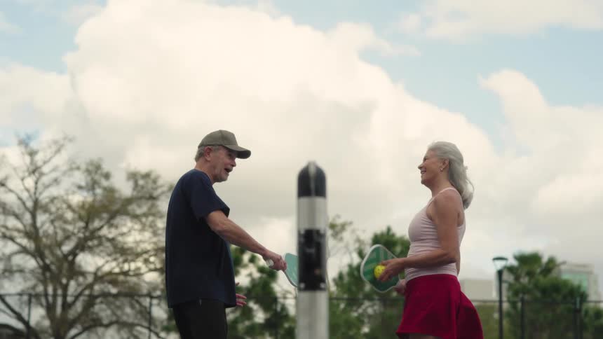 Two players discuss a pickleball game by the net