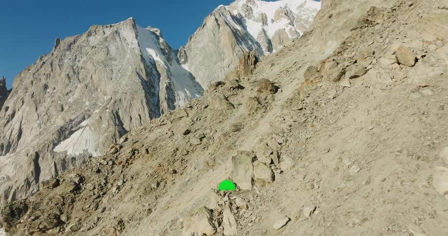 Aerial view of a green tent in the middle of a mountain cliff