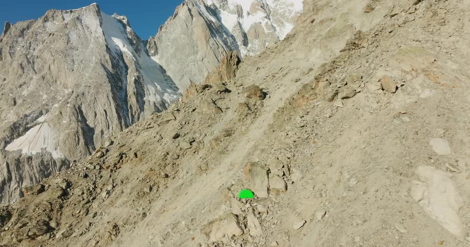 A green tent nestled amount the mountains