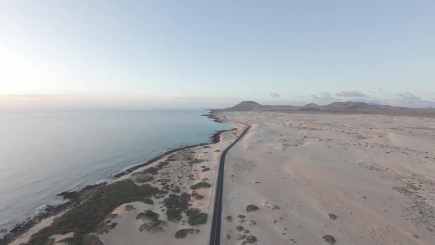 Aerial panorama of a sunrise and a desert land surrounded by the sea