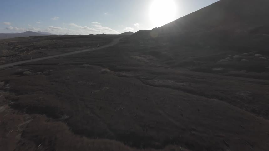 A person rides a motorcycle on a remote road in a desert valley