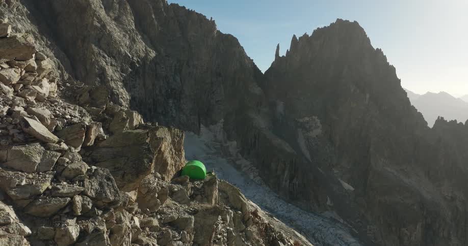 A green tent nestled in the mountains