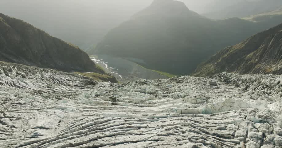 A rugged rocky mountain valley with a winding river flowing through it and extensive debris covering the landscape