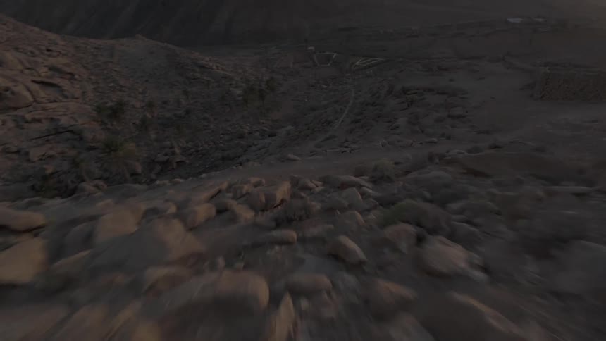 Aerial panorama of steep mountains with sunrise on the horizon