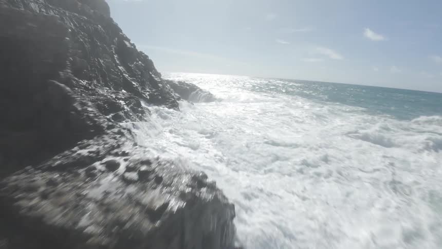 Aerial shot of turbulent sea crashing against rocky coastline