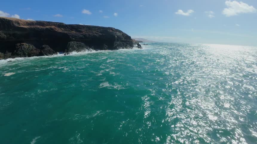 Aerial view of turquoise blue sea with rocky coastline