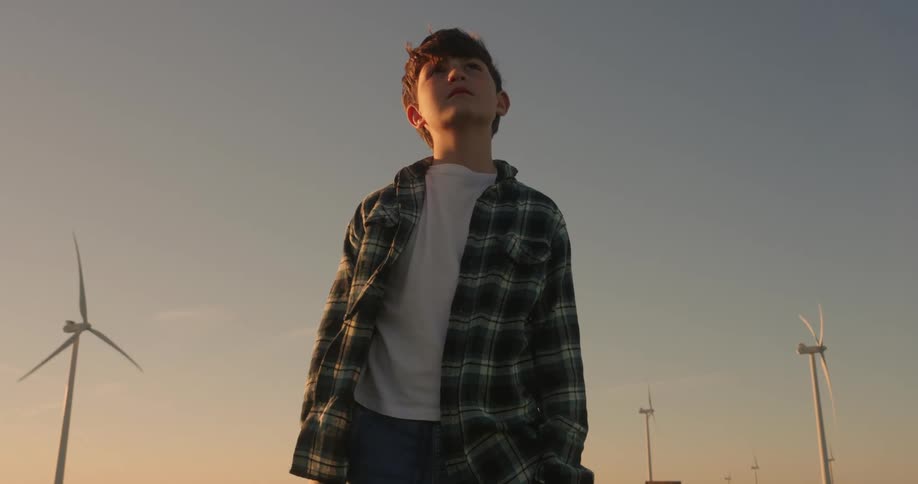 A footage of a boy standing outdoor in the windfarm