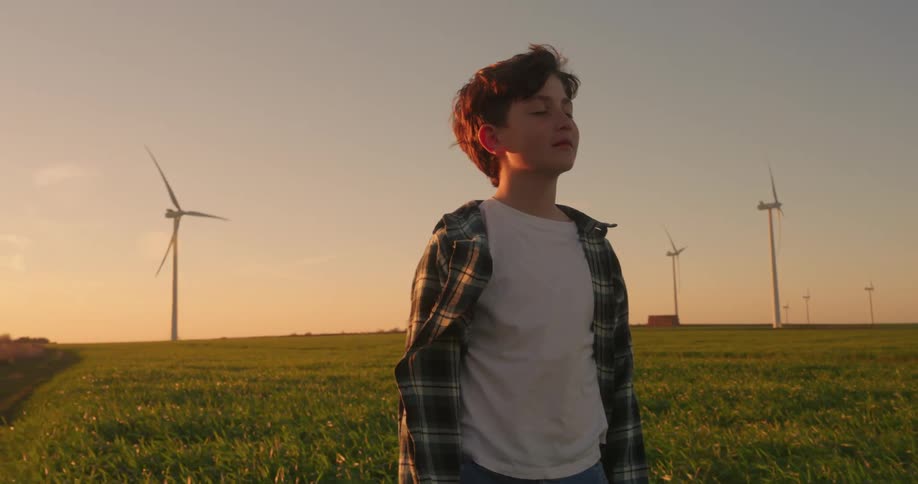 A footage of a boy contemplating on a wind farm
