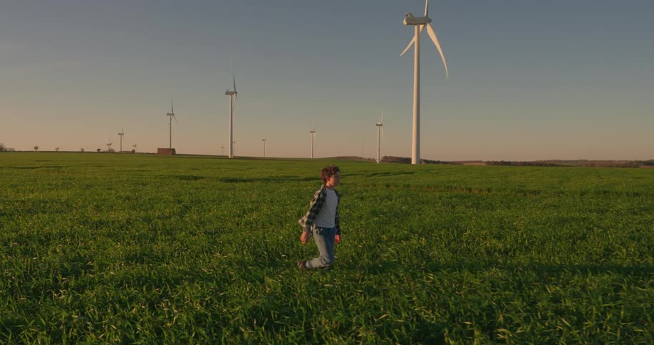 A footage of a boy walking the wind farm