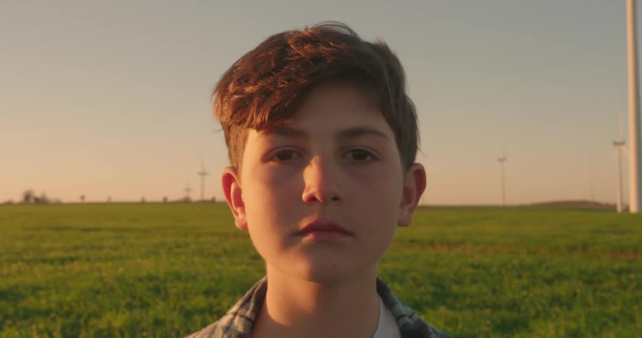 A footage of a boy standing on a green field