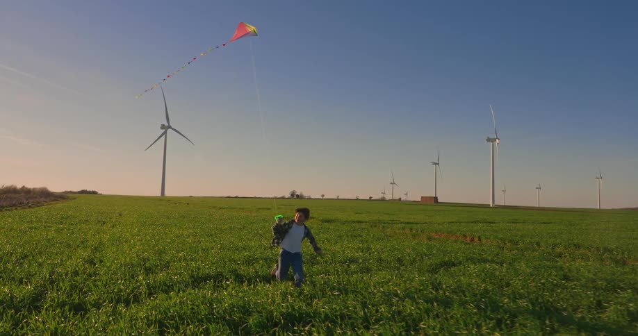 Boy running through a farm field playing with a kite