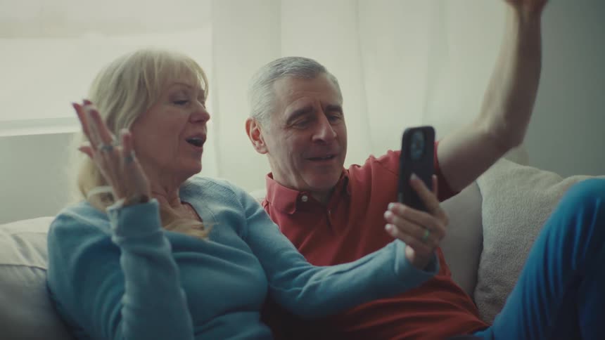 A man and woman talk and smile on a video call at home