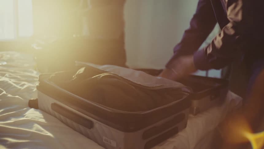 A man and woman are packing luggage for a trip