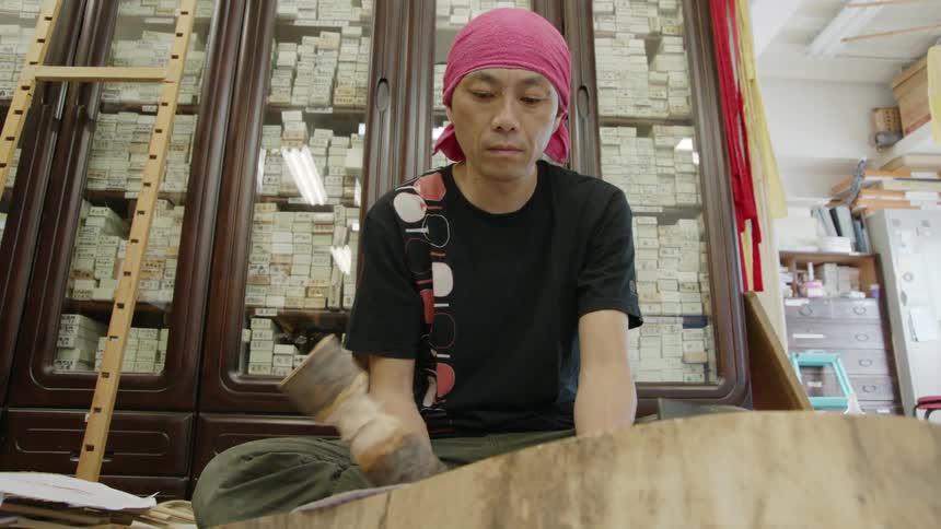 A man is hammering down paper in a shop