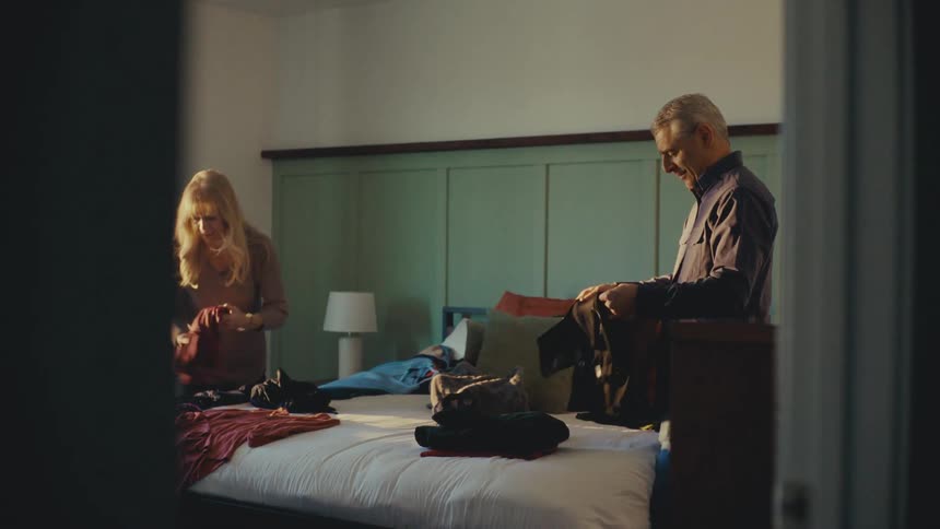 A couple are packing clothing for a trip