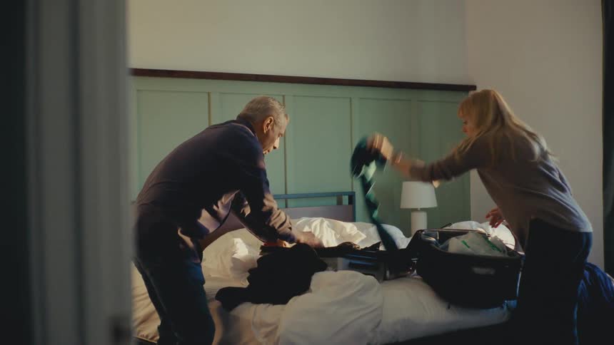 A footage of a man and a woman packing their luggage indoor